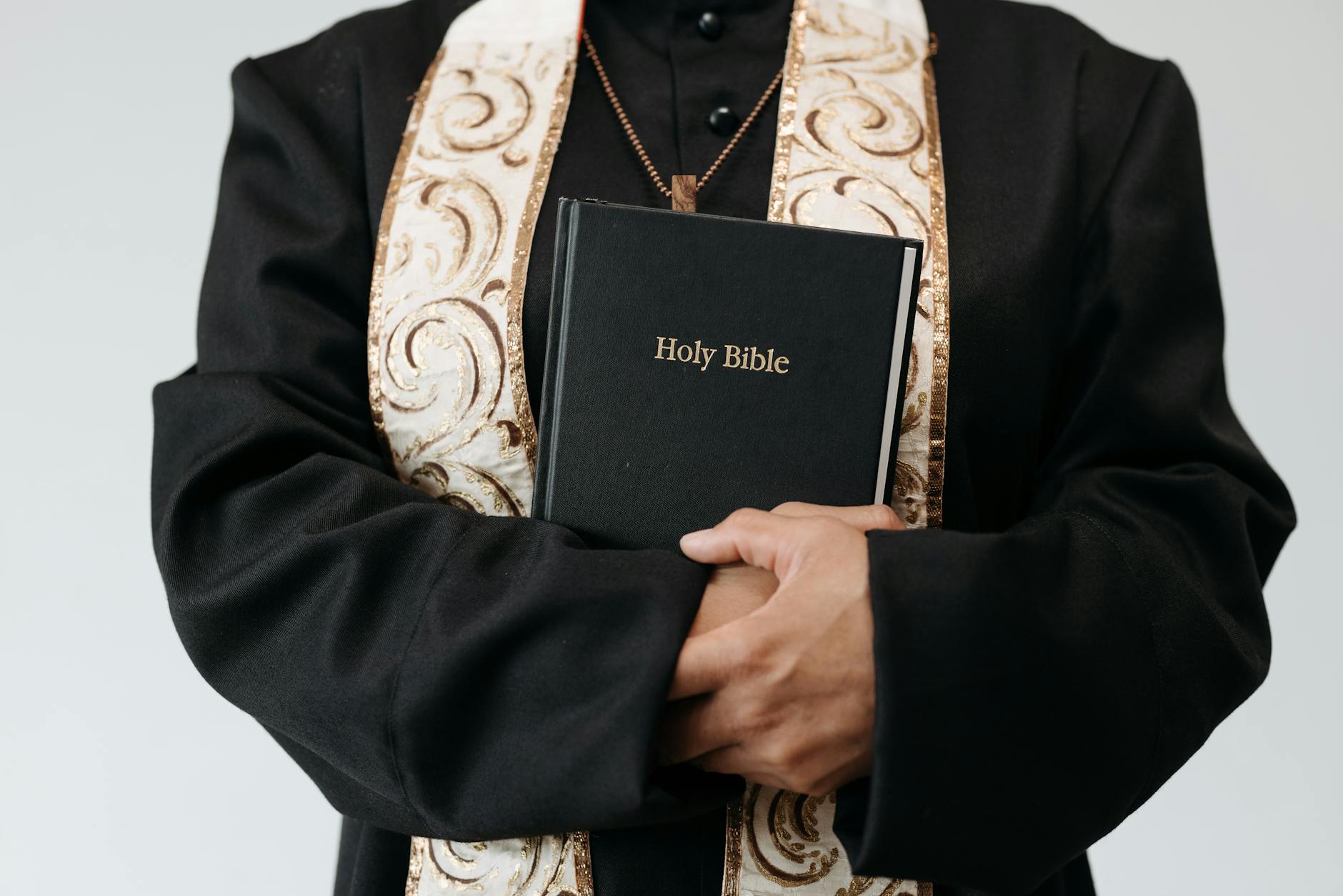 person wearing a cassock holding a bible