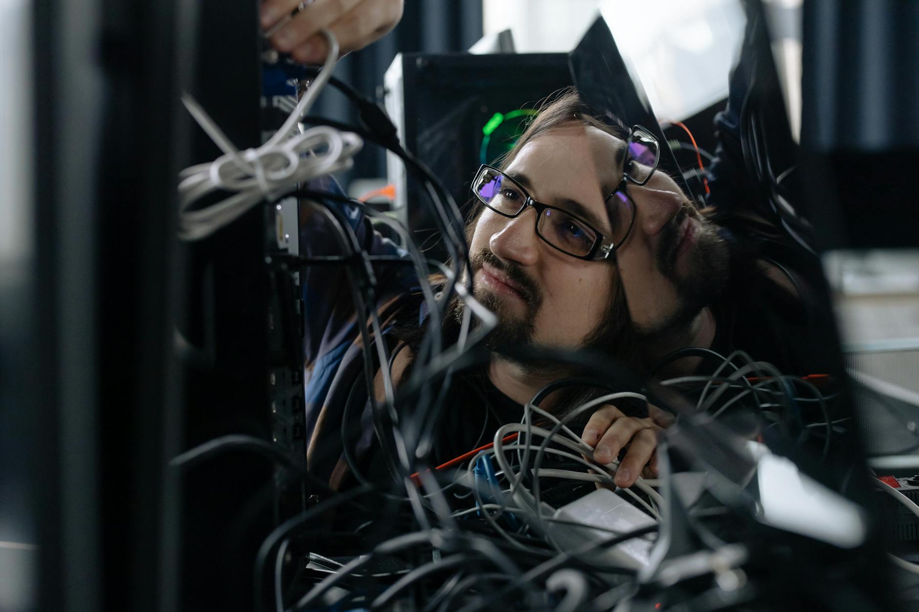 employee working through the tangle of cables behind the computer