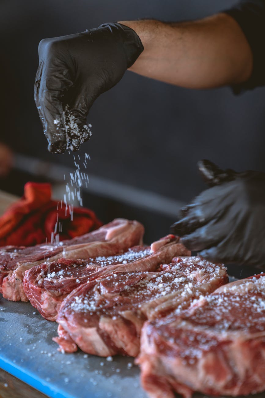 person seasoning the steak