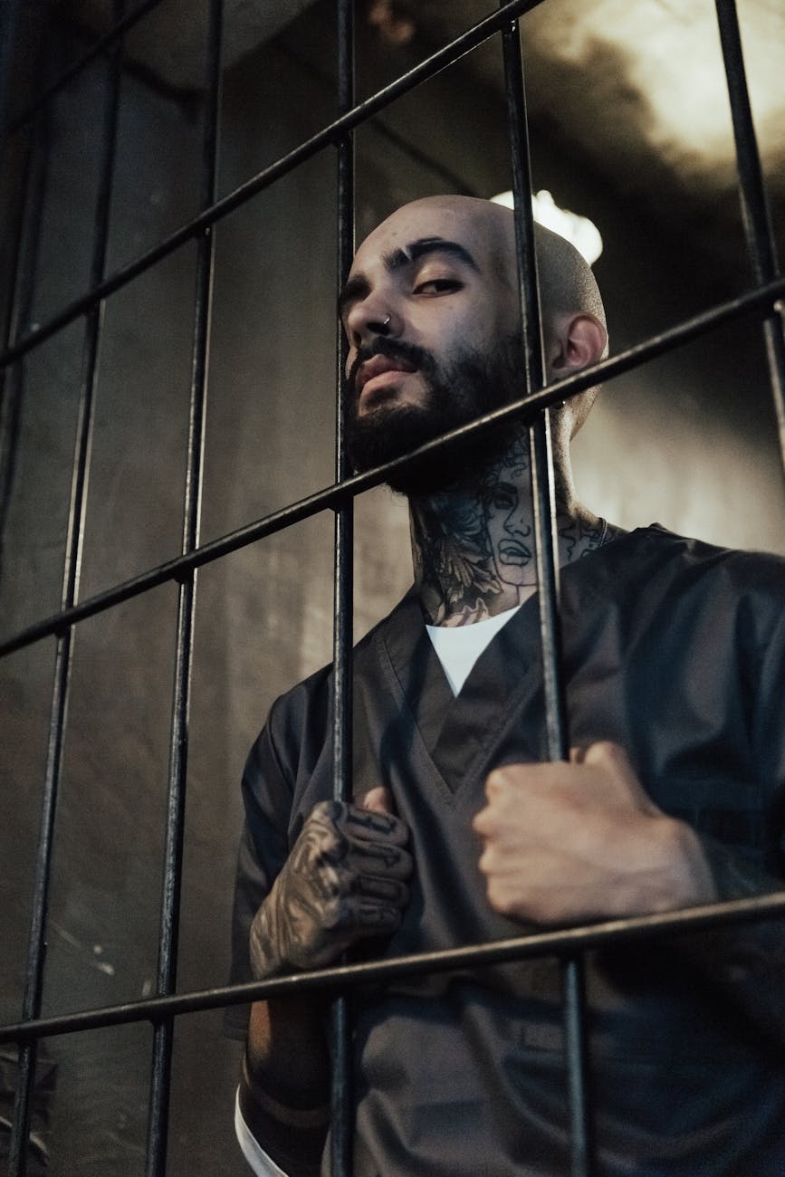 bald man with tattoo behind metal bars