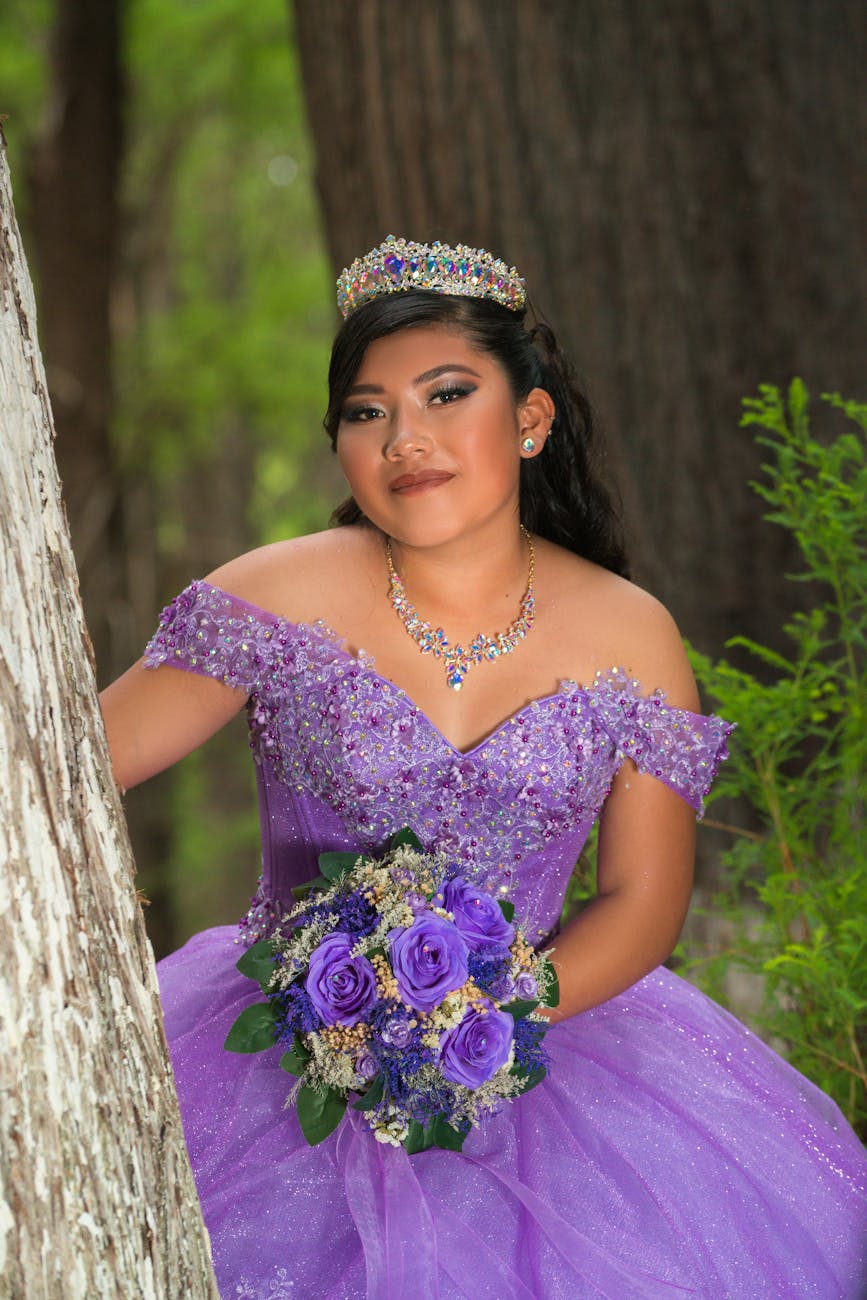 brunette woman in purple dress posing with bouquet of flowers