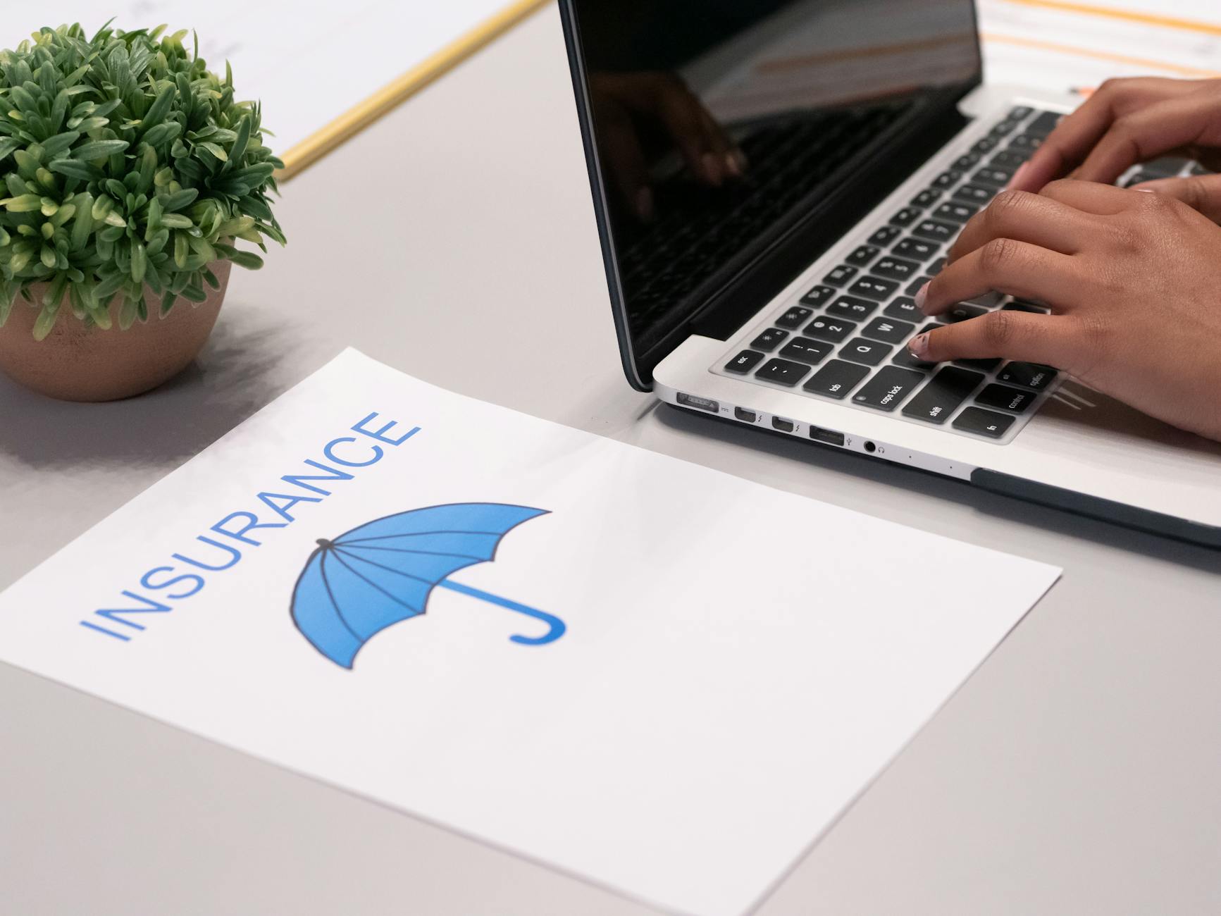 a paper beside a person typing on a laptop, Insurance Law