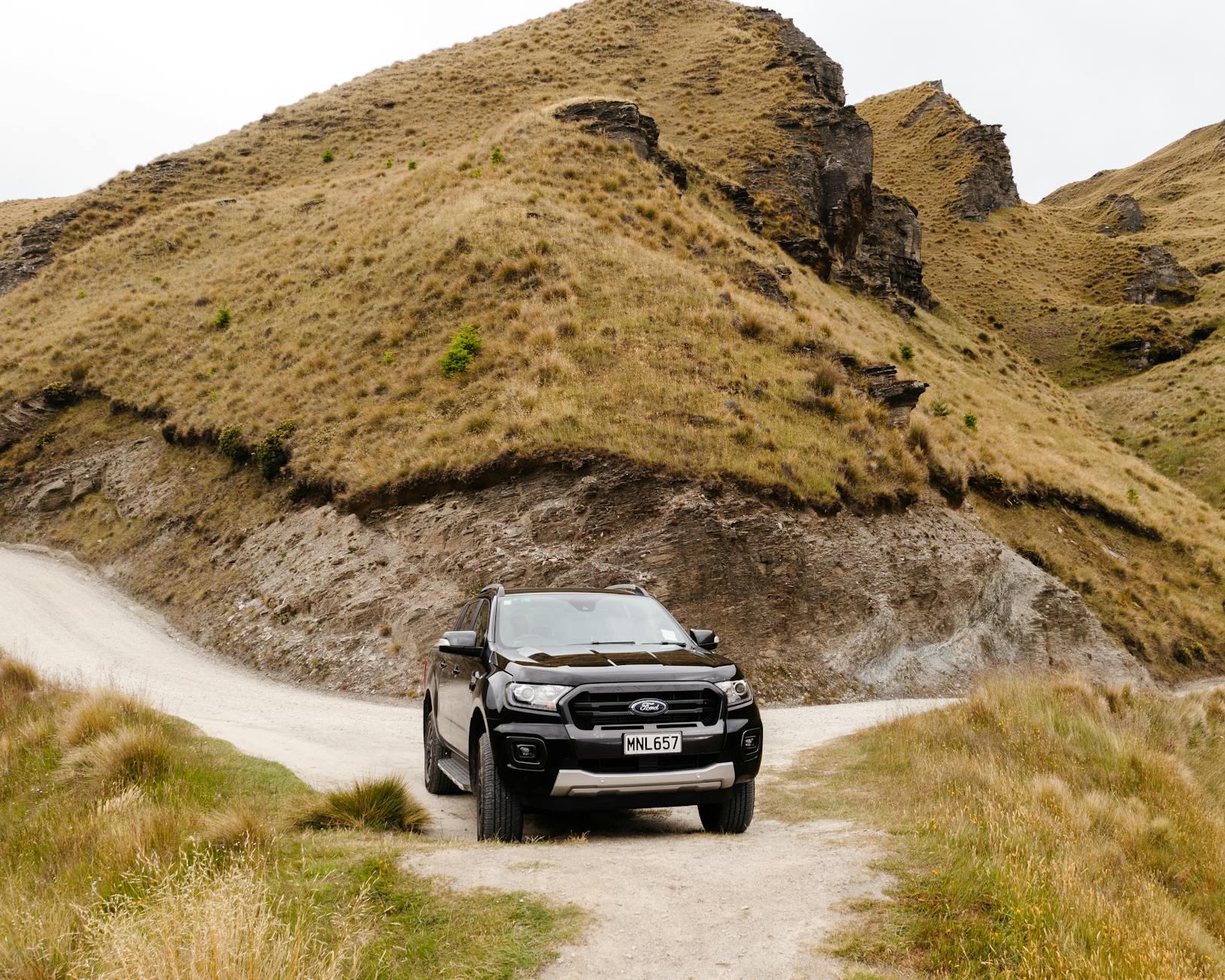 ford suv on dirt road under hill