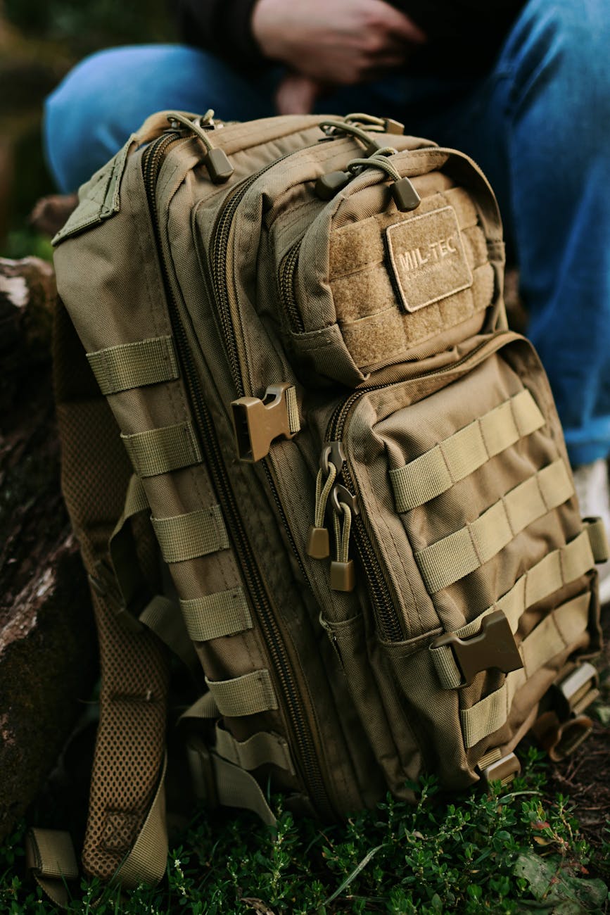 a military backpack and a man sitting in the background