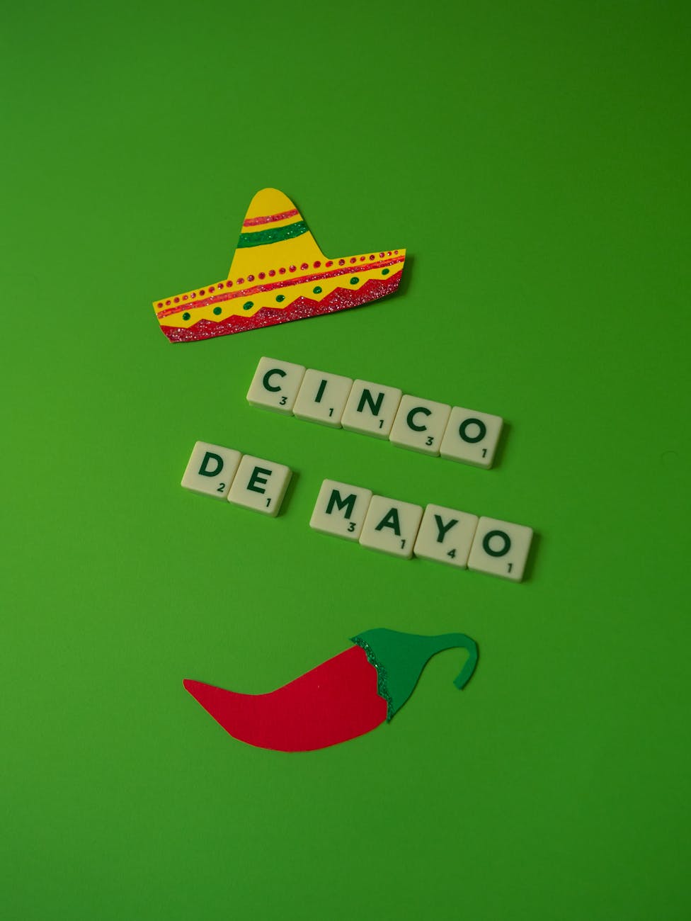 cinco de mayo text on green background beside cutouts of mexican sombrero and pepper